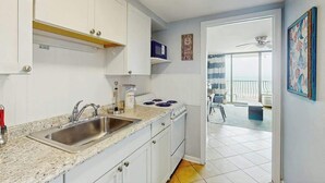 A kitchen with white cabinets, a granite countertop, and a stainless steel sink. - Palms Resort Unit 404 (Myrtle Beach)