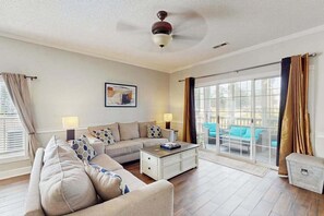 Ein Wohnzimmer mit einem Ecksofa, einem Couchtisch und einem Deckenventilator.