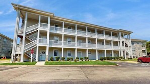 A multi-story building with balconies, a stop sign, and a clear sky. - Wild Iris Unit 101 Condo (Myrtle Beach)