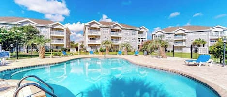 Une piscine à l’eau d’un bleu limpide, entourée d’une terrasse dallée.