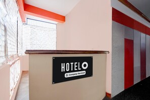 A hotel reception desk with a sign indicating it is company-serviced.
