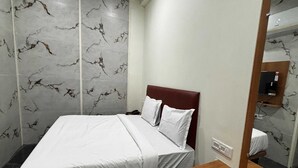 A hotel room with a bed, a wooden bedside table, a mirror, and marble-patterned walls. - Hotel O Doddabalapura (Doddaballapur)