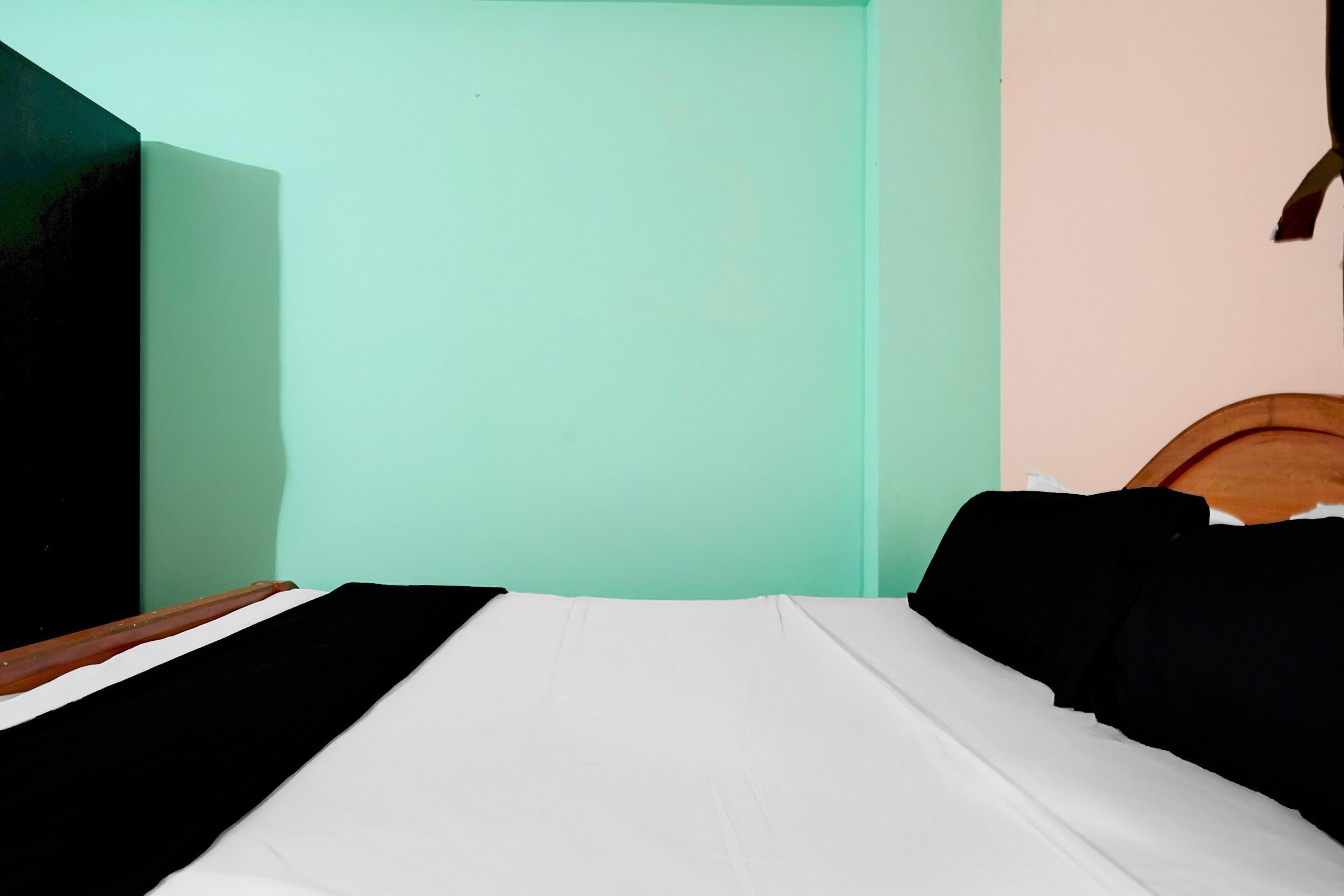 Ein Zimmer mit einem Bett, einem Holzkopfende und einer grünen Wand.