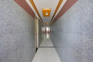 A corridor with a tiled floor, a ceiling with a recessed light fixture, and walls with a textured finish.