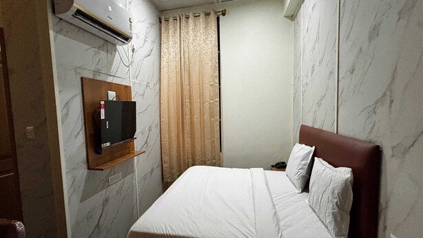 A hotel room with a bed, a TV mounted on the wall, and a window with curtains. - Hotel O Doddabalapura (Doddaballapur)