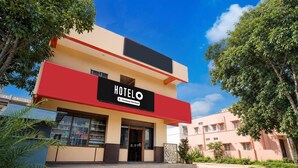 A two-story hotel with a prominent 'HOTEL' sign, a company-serviced label, and a clear sky.