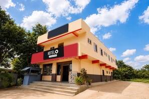 A modern hotel with a prominent red and beige facade, a visible entrance, and a clear sky.