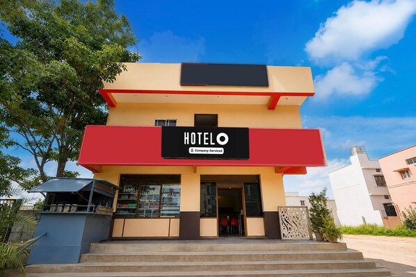 A two-story hotel with a prominent 'HOTEL' sign on the facade, a staircase leading to the entrance, and a clear blue sky in the background.