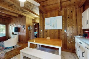 A wooden interior with a dining table, white cabinets, and a mounted artwork. - Williams Beach Bunker B (North Myrtle Beach)