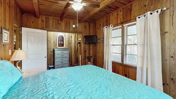 A room with a bed, a ceiling fan, a television, and wooden walls. - Williams Beach Bunker B (North Myrtle Beach)