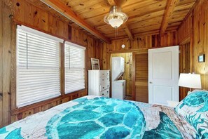 A wooden-paneled room with a bed, dresser, and a door. - Williams Beach Bunker B (North Myrtle Beach)