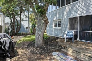 A residential backyard with a tree, a covered grill, and a patio with a chair. - Williams Beach Bunker B (North Myrtle Beach)