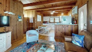 A wooden interior with a television, white furniture, and a kitchen area. - Williams Beach Bunker B (North Myrtle Beach)