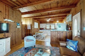 A wooden interior with a television, white furniture, and a kitchen area. - Williams Beach Bunker B (North Myrtle Beach)