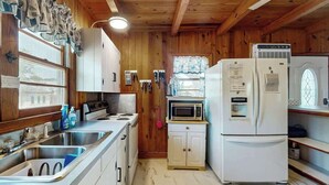 A compact kitchen with wooden walls, a sink, a stove, a microwave, and a refrigerator. - Williams Beach Bunker B (North Myrtle Beach)