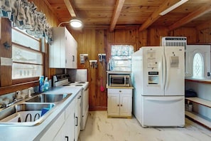 A compact kitchen with wooden walls, a sink, a stove, a microwave, and a refrigerator. - Williams Beach Bunker B (North Myrtle Beach)