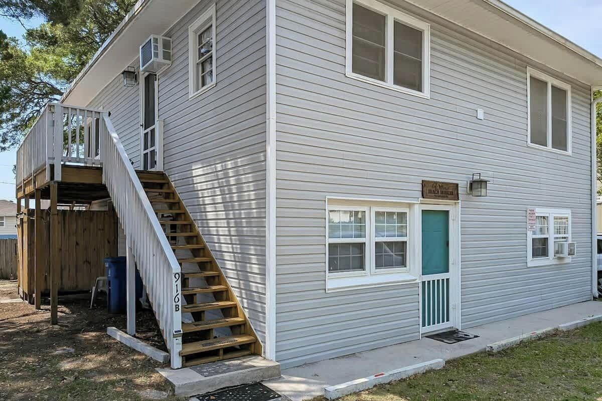 Une maison à deux étages avec un porche à l’avant, un escalier menant à l’étage supérieur et un petit jardin devant.