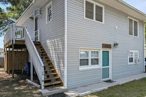 A two-story house with a front porch, a staircase leading to the upper floor, and a small front yard. - Williams Beach Bunker B (North Myrtle Beach)