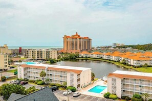 A hotel with multiple buildings, a swimming pool, and a body of water in the background. - Beach Cottages at OD - 11B (North Myrtle Beach)