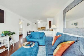 Un salon avec un canapé bleu, une table basse sur laquelle se trouve un magazine et une plante.