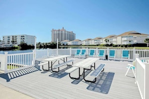 A deck with picnic tables and chairs, overlooking a body of water and buildings. - Beach Cottages at OD - 11B (North Myrtle Beach)