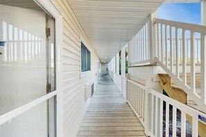 A covered wooden corridor with white railings and a wooden deck on one side. - Beach Cottages at OD - 11B (North Myrtle Beach)