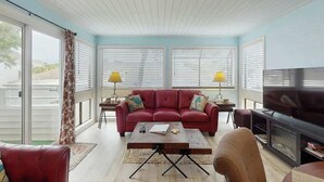 Ein Wohnzimmer mit einem roten Sofa, einem Couchtisch, einem Fernseher und einem Kamin.