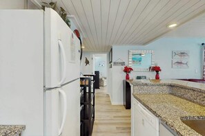 Une cuisine moderne avec un réfrigérateur blanc, un plan de travail en granit et un revêtement de sol en bois.