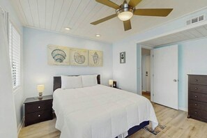 A bedroom with a bed, nightstands, a ceiling fan, artwork on the wall, and a dresser. - Arcadian Dunes 12-245 (Myrtle Beach)