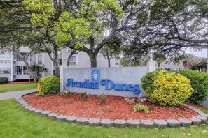 A sign for Arclandian Dunes with a landscaped area featuring a hedge and mulch. - Arcadian Dunes 12-245 (Myrtle Beach)
