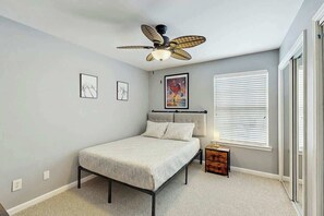 A bedroom with a bed, a ceiling fan, a window with blinds, and a nightstand. - Sterling Pointe 113-F at Wachesaw III (Murrells Inlet)