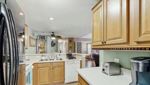 A kitchen with wooden cabinets, a dishwasher, a toaster, and a coffee maker. - Sterling Pointe 113-F at Wachesaw III (Murrells Inlet)