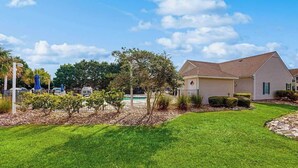 A residential area with a swimming pool, a house with a garage, and a well-maintained lawn. - Sterling Pointe 113-F at Wachesaw III (Murrells Inlet)