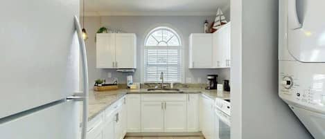 A modern kitchen with white cabinets, a built-in oven, and a dishwasher.