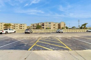 A parking lot with multiple cars, a building with balconies, and a clear sky. - A Place at the Beach IV - 235 (Myrtle Beach)