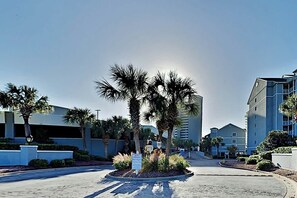 A hotel entrance with palm trees, a paved driveway, and modern buildings in the background. - Sea Watch Unit 1605 Condo (Myrtle Beach)