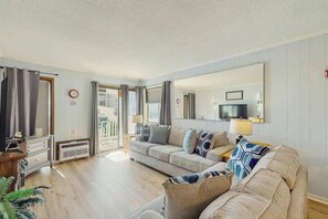 A living room with a sofa set, a television, and a mirror on the wall. - A Place at the Beach VI - 105 (Myrtle Beach)