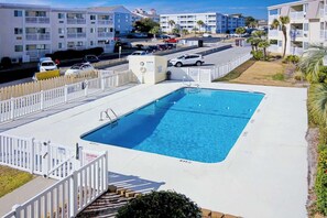 A swimming pool with a white fence, a lifeguard stand, and a view of multi-story buildings in the background. - A Place at the Beach VI - 105 (Myrtle Beach)