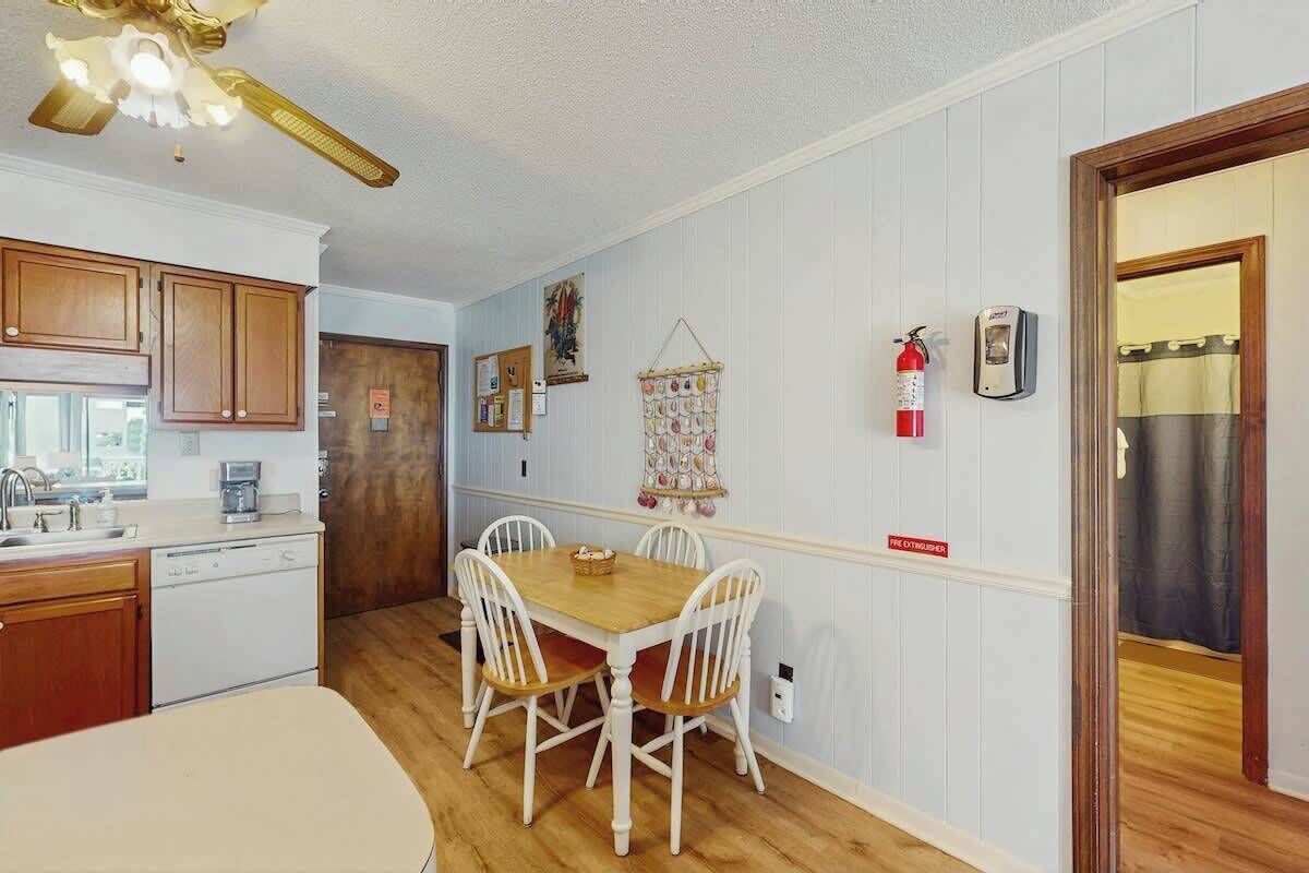 Eine kleine Küche mit Essbereich, Holzschränken, einem weißen Kühlschrank und einem Deckenventilator.