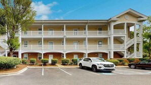 Un hotel a più piani con un cortile centrale, balconi e un'area parcheggio.