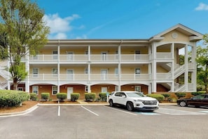 Ein mehrstöckiges Hotel mit Innenhof, Balkonen und einem Parkplatz.