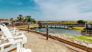 Vista al agua con un muelle de madera, sillones de descanso y cielo despejado.