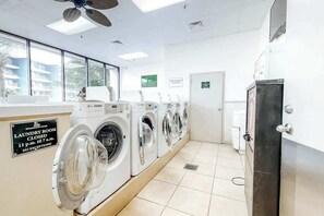 A laundry room with multiple washing machines, a closed door, and a sign indicating closure times. - Myrtle Beach Resort 344B (Myrtle Beach)