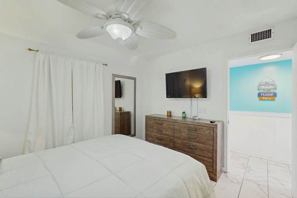 A bedroom with a bed, a dresser, a television, and a wall with a poster.