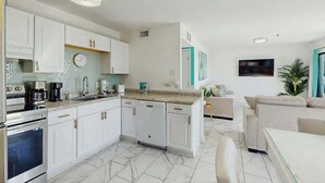 Una cocina moderna con armarios blancos, horno empotrado y cafetera.