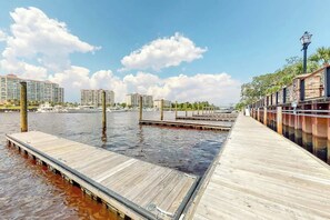 Een pand aan het water met houten steigers die het water in reiken, omringd door gebouwen en een heldere lucht.