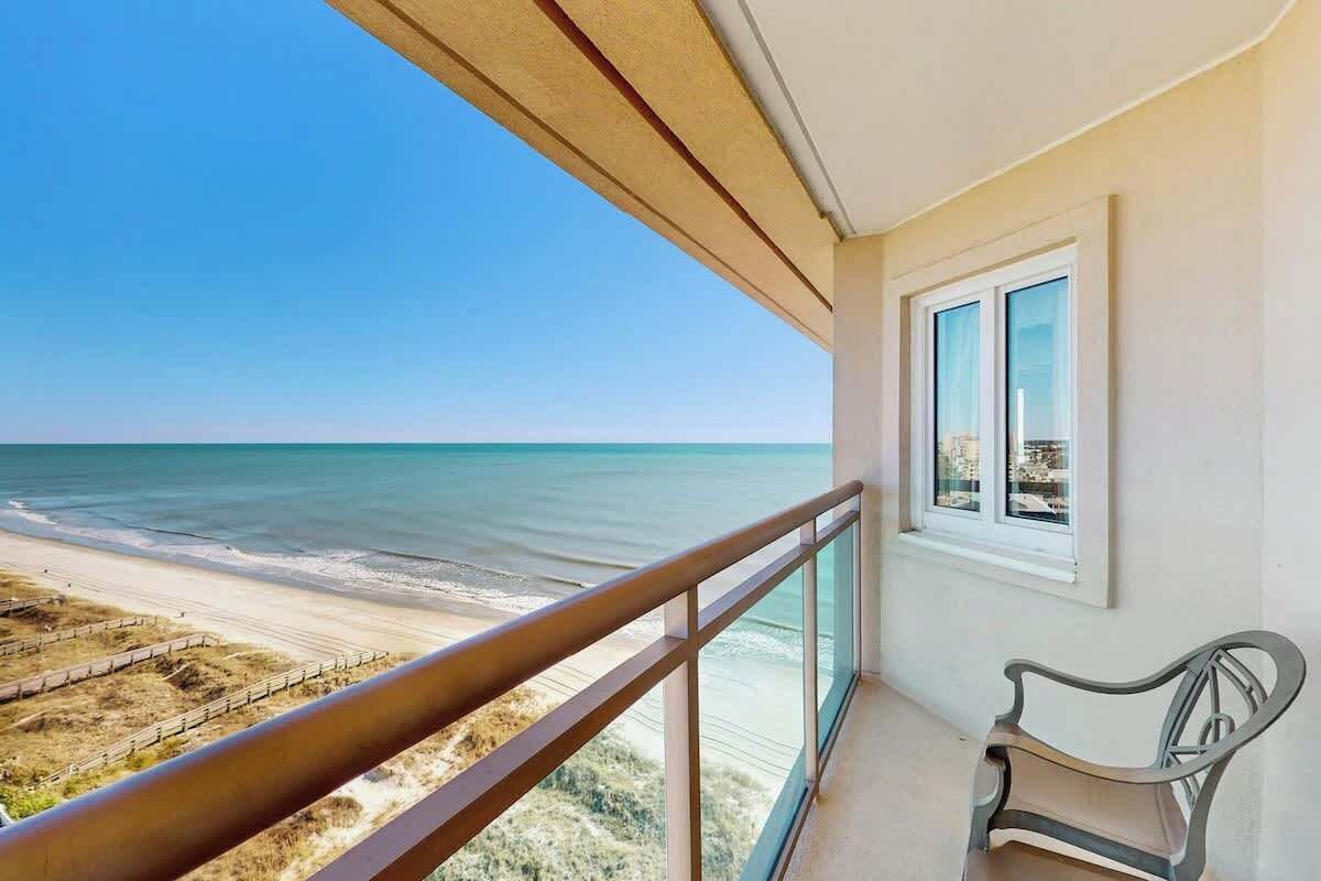 A balcony with a view of the beach and ocean.