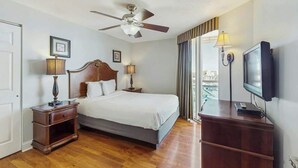 A hotel room with a bed, a ceiling fan, a television, and a view of the city through the window. - Bahama Sands Unit PH02 (North Myrtle Beach)