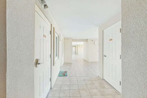 Un couloir avec des portes blanches et un sol carrelé.