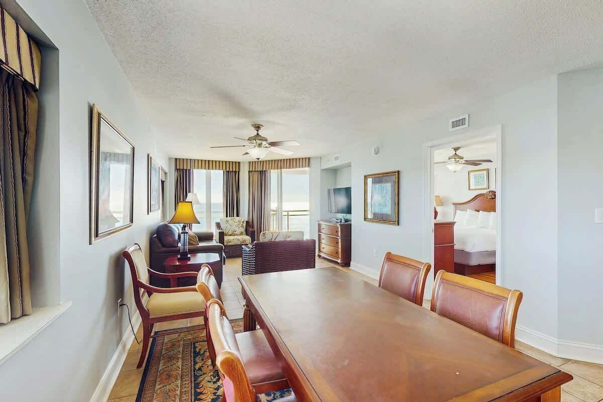 A hotel room with a dining area, a sofa, a television, and a bed.